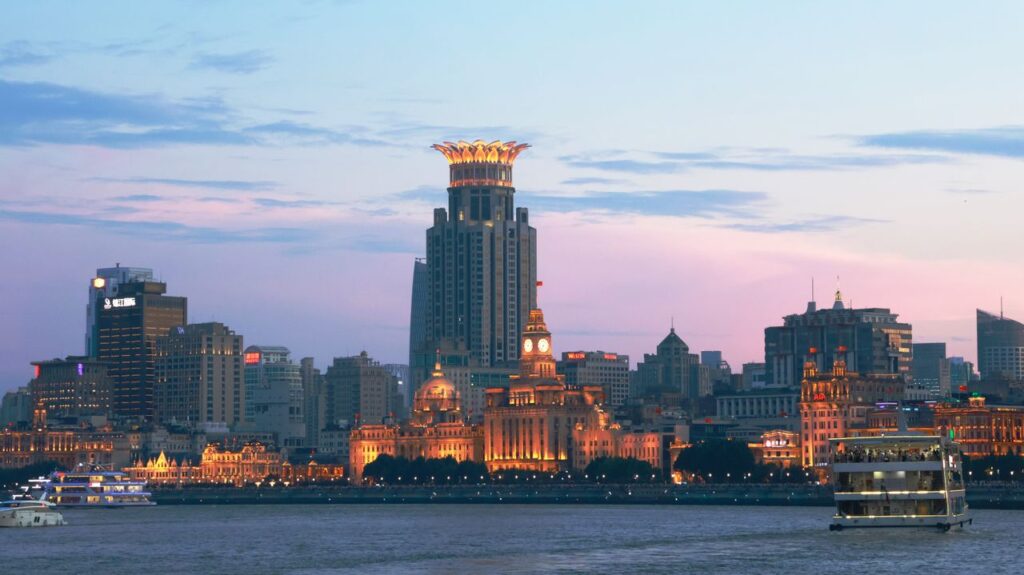 Shanghai Tour: Unveil the Timeless Fusion of Colonial Elegance & Futuristic Modernity Panoramic view of the illuminated Shanghai skyline and Huangpu River during twilight with iconic landmarks.