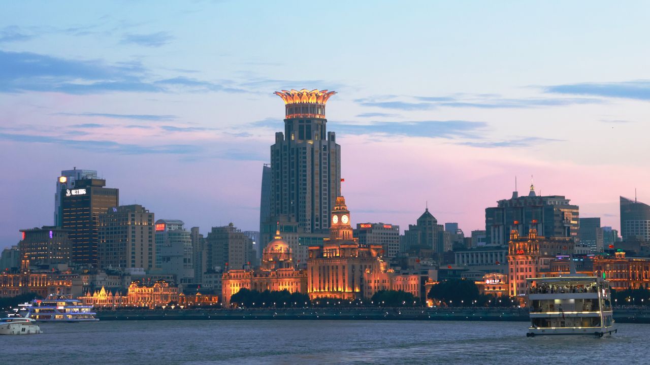 Shanghai Tour: Unveil the Timeless Fusion of Colonial Elegance & Futuristic Modernity Panoramic view of the illuminated Shanghai skyline and Huangpu River during twilight with iconic landmarks.